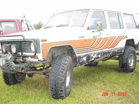 1978 Ford Bronco - Nissan Patrol off-road vehicle with distinctive orange stripe graphics and large tires.