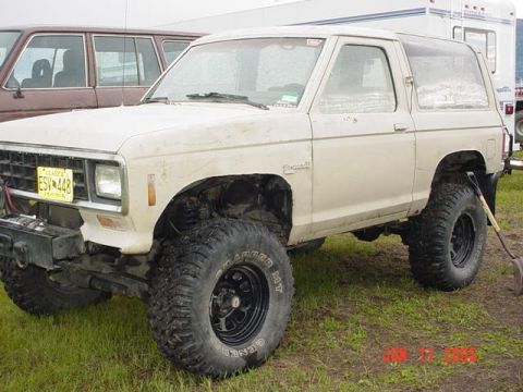 1978 Ford Bronco - A lifted Ford Bronco II is parked on grass with a shovel leaning against it.