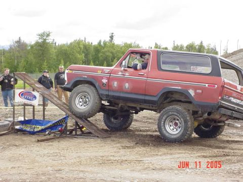 1978 Ford Bronco - A red 1978 Ford Bronco is positioned on a ramp during an event, with spectators watching.