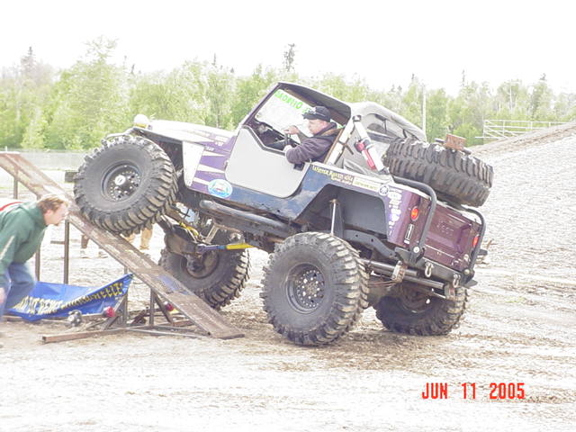 Modified Jeep CJ-7 with large tires climbing a ramp. A person watches from the side. Date stamp reads JUN 11 2005