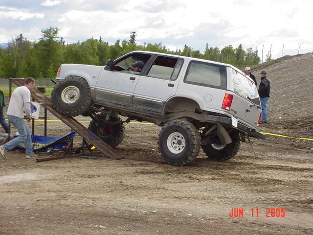 Silver SUV with large off-road tires on a metal ramp, driver visible. Date stamp reads JUN 11 2005
