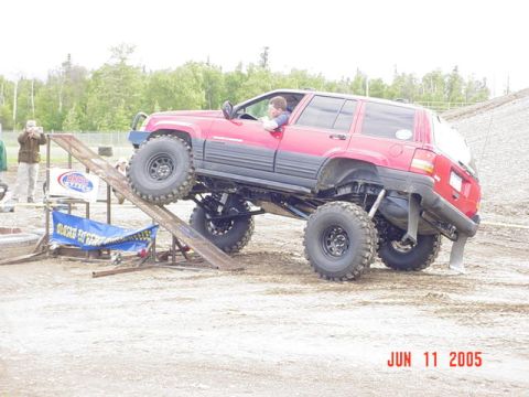1978 Ford Bronco - Modified red Jeep Grand Cherokee attempting an obstacle at an event.