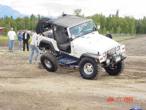 1978 Ford Bronco - A white Jeep Wrangler is shown with a lifted suspension and off-road tires, with people standing nearby.