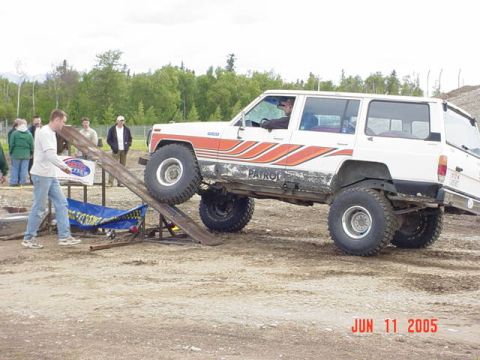 1978 Ford Bronco - A white SUV with orange stripes is positioned on a ramp, with the word "PATROL" visible on its side.