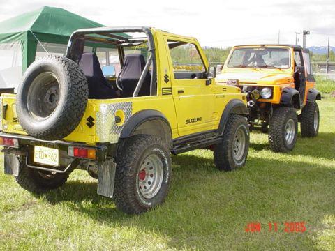 1978 Ford Bronco - Two Suzuki Samurai vehicles are parked on grass, one yellow and one orange.