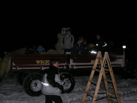 2001 Jeep Wrangler - A wagon filled with people and hay is parked outdoors at night, with a ladder nearby.