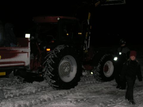 2001 Jeep Wrangler - A tractor and trailer are seen in a snowy environment at night with people nearby.