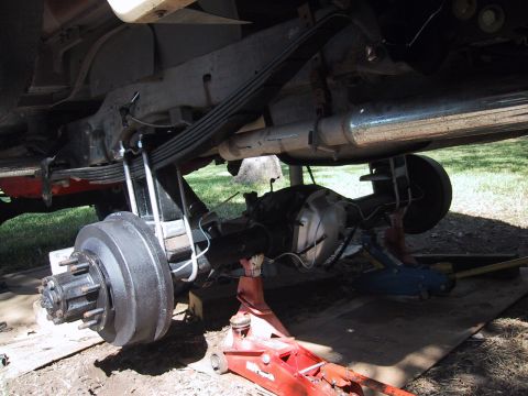 1990 Ford Bronco - Vehicle's rear axle and suspension components are visible, supported by hydraulic jacks.