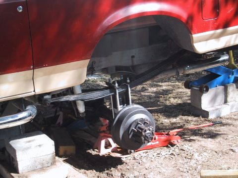 1990 Ford Bronco - The rear suspension of a 1990 Ford Bronco, showing leaf springs and brake drum, is supported by jacks.