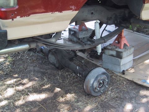 1990 Ford Bronco - Vehicle's rear axle removed for maintenance, showing suspension components and frame.