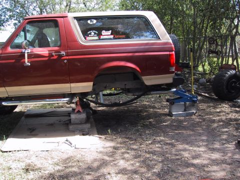 1990 Ford Bronco - This red Ford Bronco is raised on jack stands, suggesting maintenance or modification work is underway.