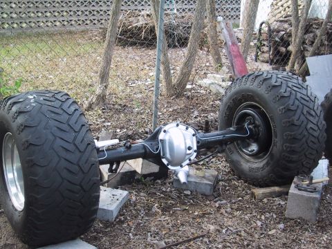 1990 Ford Bronco - A rear axle assembly with large tires is shown outdoors, supported by blocks.