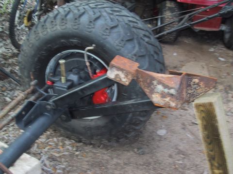 1990 Ford Bronco - A close-up view shows a large tire and part of a vehicle's suspension system, including red brake calipers.