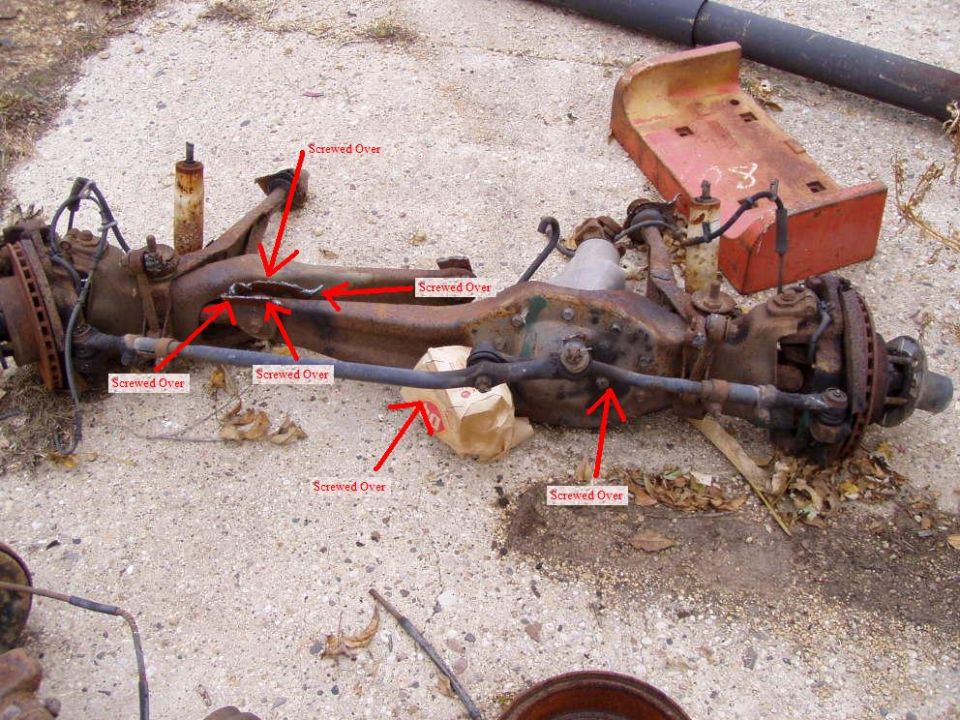 Rusty front axle assembly with red arrows pointing to various bolts labeled 'Screwed Over'