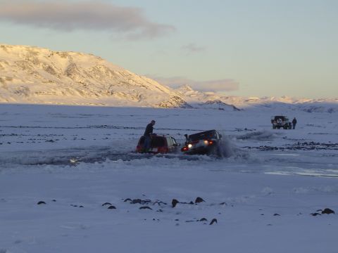 2001 Jeep Wrangler - Two Jeep Wranglers navigate icy terrain with a person on top of one vehicle, while another vehicle and people are visible in the distance.