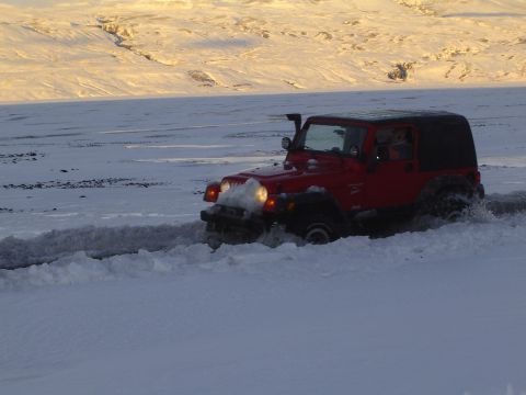 2001 Jeep Wrangler - A red Jeep Wrangler navigates through a snowy landscape, equipped with a snorkel for off-road adventures.