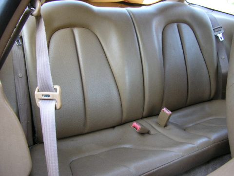 1994 Ford Probe - Interior view of tan leather rear seats with seatbelts and buckle receivers.