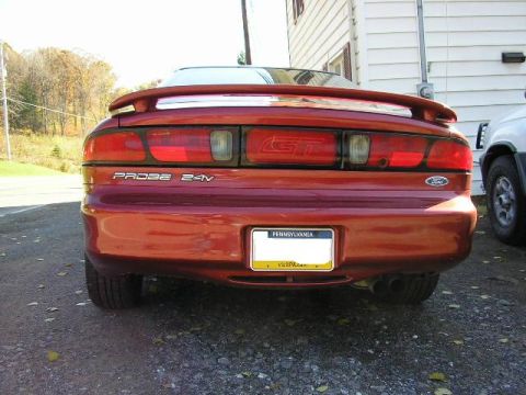1994 Ford Probe - The rear of a red 1994 Ford Probe GT is visible, parked next to another vehicle.