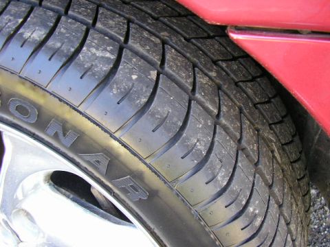 1994 Ford Probe - A close-up view shows the tread of a car tire and a portion of the vehicle's red fender.