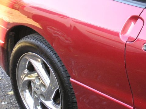 1994 Ford Probe - Side view of a red car, showing the fender, door, and wheel. The body style is consistent with a 1994 Ford Probe.