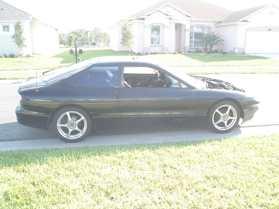 Black 1994 Ford Probe parked on street, hood up