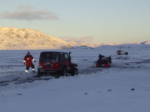 2001 Jeep Wrangler - Multiple Jeeps navigate a snowy terrain with people assisting. The red Jeep TJ is viewed from the rear.