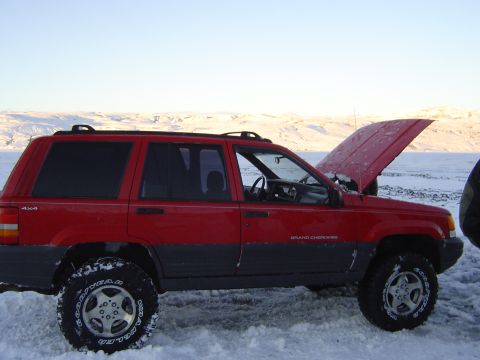 2001 Jeep Wrangler - This red Jeep Grand Cherokee, likely from the mid-1990s, sits in a snowy landscape with its hood raised.