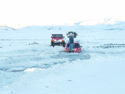 2001 Jeep Wrangler - Two vehicles are stuck in a snowy landscape, with a person standing on top of one of them.