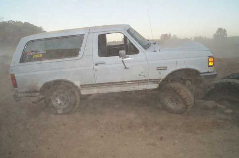 1988 Ford Bronco - This white Ford Bronco is seen from the side, kicking up dust on an off-road trail.