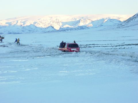 2001 Jeep Wrangler - People attempt to free a red SUV stuck in a snowy landscape with mountains in the distance.