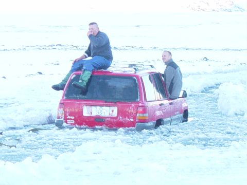 2001 Jeep Wrangler - Two men sit on and in a red Jeep Grand Cherokee stuck in a snowy landscape. The license plate reads LO-351.
