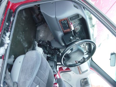 2001 Jeep Wrangler - The interior of a red vehicle shows snow accumulation on the floor and seats, with the dashboard and steering wheel in view.