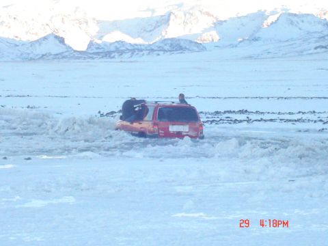 2001 Jeep Wrangler - SUV stuck in snow with people on the roof, mountains visible in the distance.