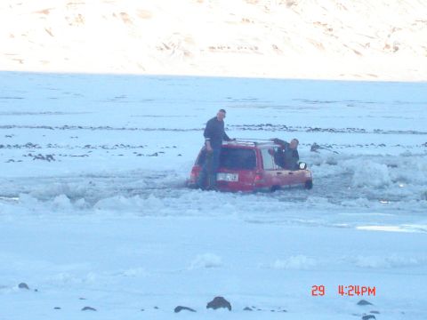 2001 Jeep Wrangler - A red 2001 Jeep TJ is stuck in a snowy landscape with two individuals near the vehicle.