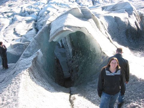 1993 Ford Bronco - Two people explore a large ice cave on a glacier, with a third person visible in the distance.