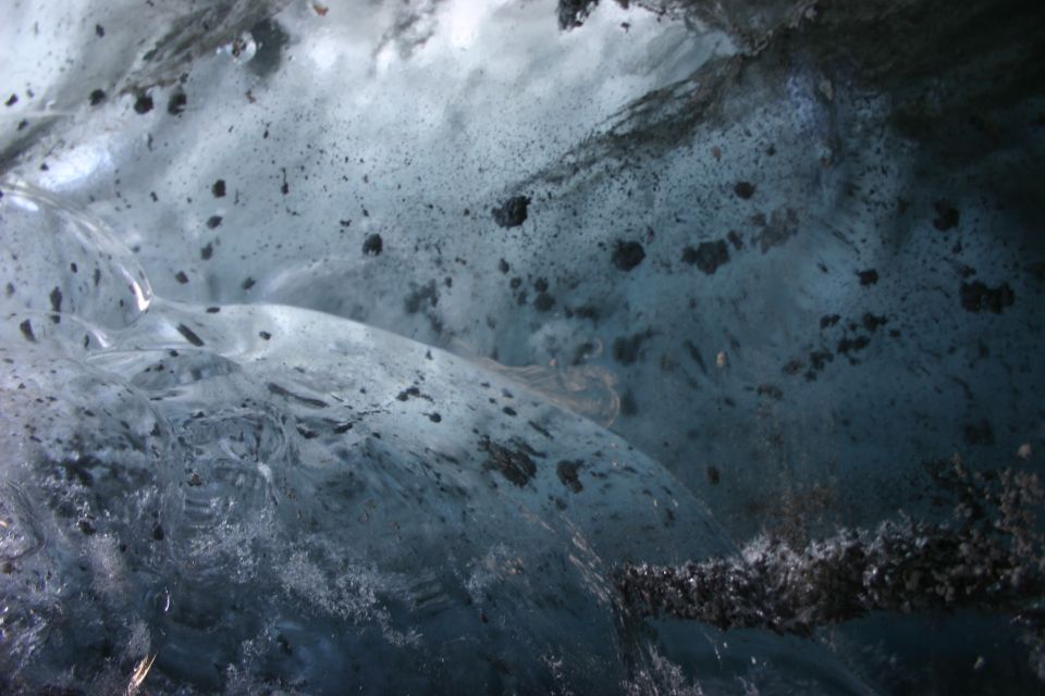 Close-up of ice cave walls with dark debris embedded in the ice