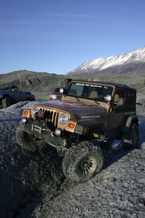 2003 Jeep TJ - A 2003 Jeep TJ navigates a glacier with snow-capped mountains in the background.