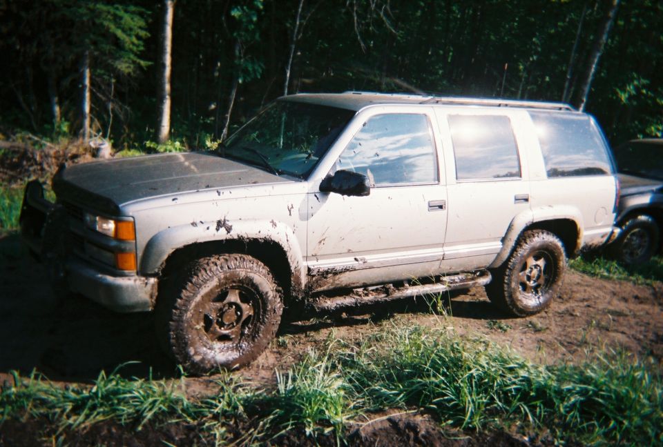 Silver SUV, 3q-front view, covered in mud. Appears to be a 1995 model