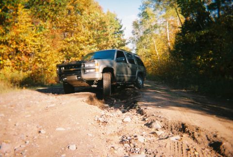2000 Chevrolet Tahoe - A gray Chevrolet Tahoe navigates a rough dirt road surrounded by fall foliage.