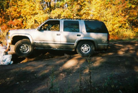 2000 Chevrolet Tahoe - This silver SUV navigates a dirt path surrounded by vibrant autumn trees.