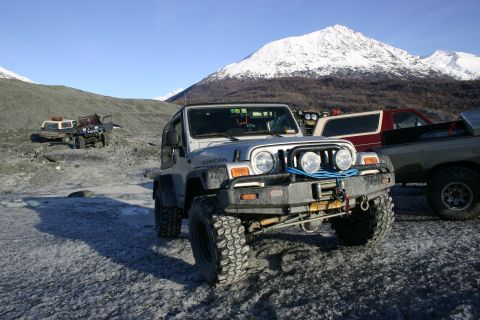 2003 Jeep TJ - Several off-road vehicles are parked on a glacial surface with snow-capped mountains in the distance.