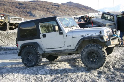 2003 Jeep TJ - A silver Jeep Wrangler Rubicon is parked on a snowy, rocky terrain with mountains in the background.