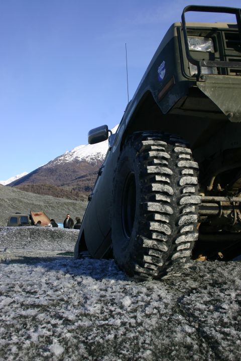 2003 Jeep TJ - A green 2003 Jeep TJ is parked on icy terrain with snow-capped mountains in the background.