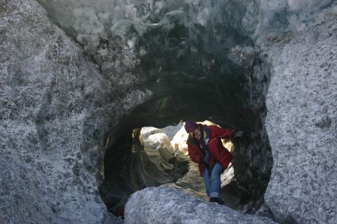 2003 Jeep TJ - A person stands at the entrance of a natural ice cave, with glacial formations visible within.