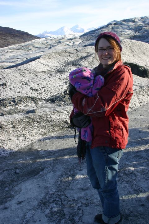 2003 Jeep TJ - A woman and baby stand on a glacier, with a vast icy landscape and distant mountains under a clear blue sky.