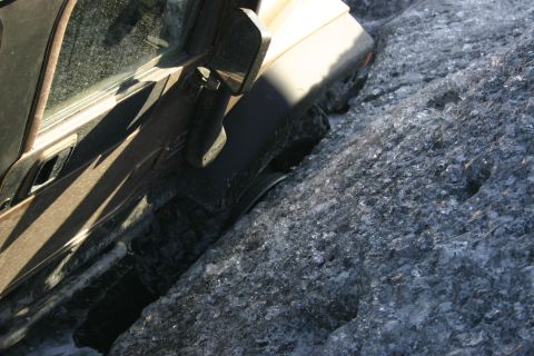 2003 Jeep TJ - A tan Jeep Wrangler is partially submerged in icy water, with its side visible against a textured, frozen landscape.