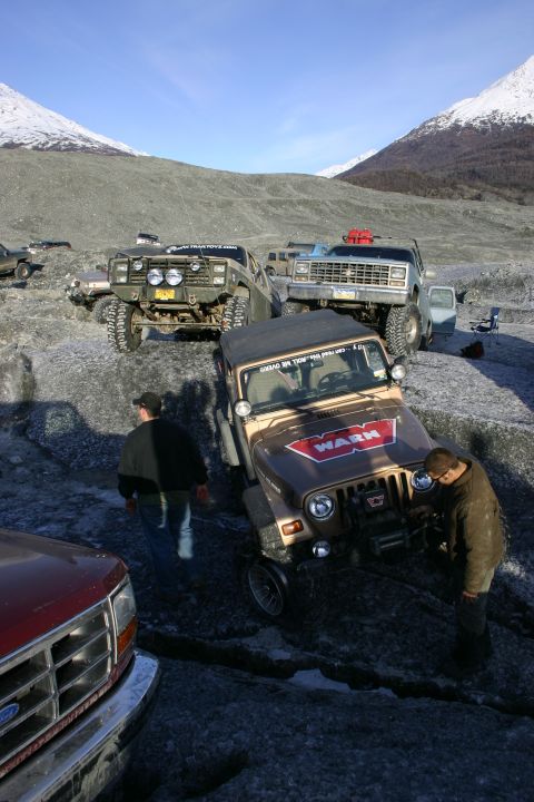 2003 Jeep TJ - A group of off-road vehicles are parked on a glacier, with people interacting with one of the Jeeps.