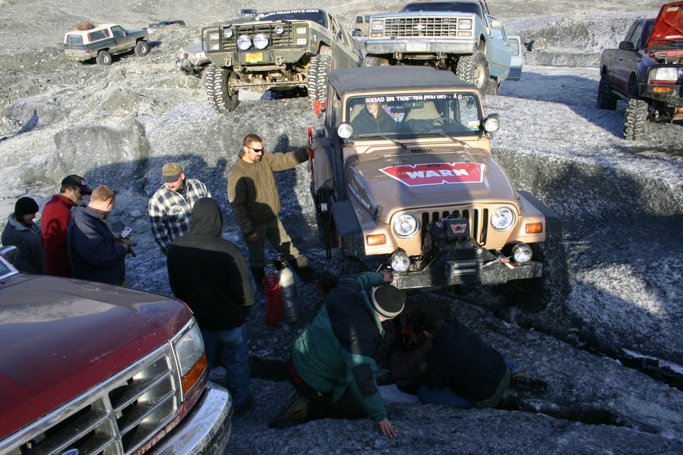 Tan Jeep Wrangler TJ with WARN winch and decal, front 3/4 view, on icy terrain