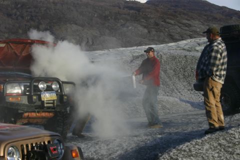 2003 Jeep TJ - A 2003 Jeep TJ is seen with smoke coming from its engine bay, while two men stand nearby.