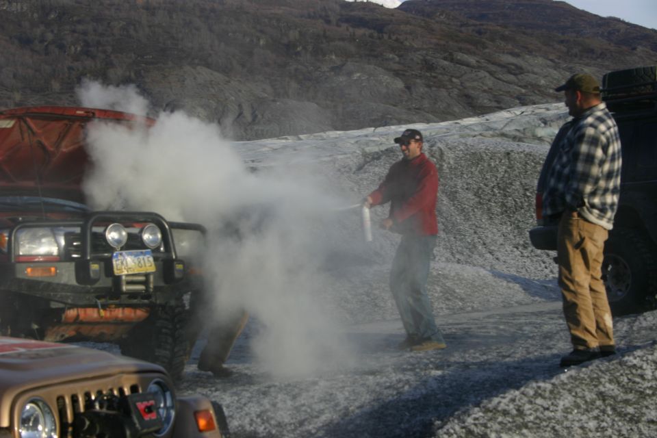 2003 Jeep TJ with smoke billowing from the front, two men nearby